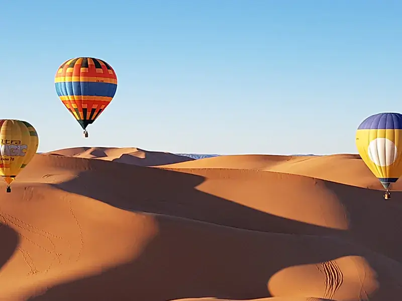 Colorful balloons over sandy dunes.